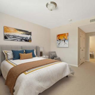 A modern bedroom with stylish decor and artwork, featuring a comfortable bed and neutral color palette.