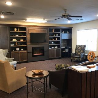 A cozy living room with modern furnishings, featuring a fireplace, television, and built-in shelves.