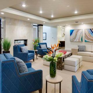 A modern living room with blue chairs, abstract artwork, and a cozy atmosphere.
