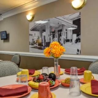 A neatly set dining table with colorful tableware and a vase of yellow flowers.