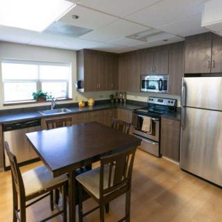 A modern kitchen featuring wooden cabinets, stainless steel appliances, and a dining area with a table and chairs.