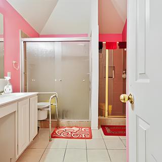 A stylish bathroom with pink walls, featuring a vanity, mirror, and glass shower enclosure.