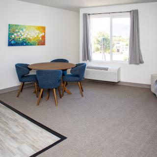 A bright and modern dining area featuring a round table and blue chairs, complemented by an artistic wall decoration.