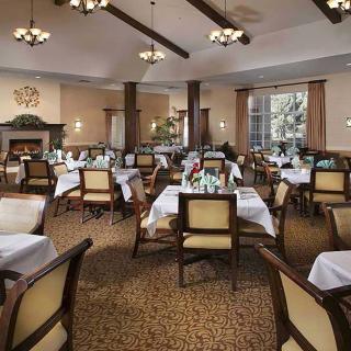 An elegant dining room with neatly arranged tables and chairs, adorned with chandeliers.