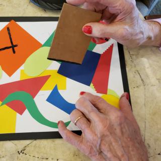 A person arranging colorful paper shapes on a table.