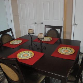 A dining table set with red placemats and candles.
