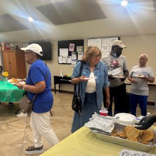 A group of people enjoying a buffet at an indoor social event.