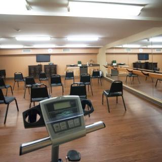An exercise room with chairs arranged facing mirrors and screens.