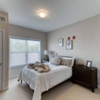 A cozy bedroom with a large window and neutral decor.