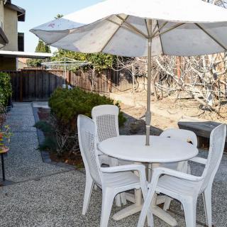A patio area with a white table, chairs, and a large umbrella.