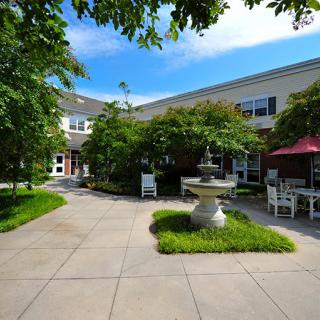 A tranquil courtyard with a central fountain, surrounded by lush greenery and seating areas.