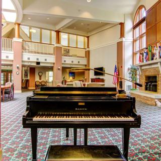 A grand piano in a spacious lobby with large windows and comfortable seating.