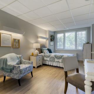 A cozy bedroom with a bed, chairs, and a window view.