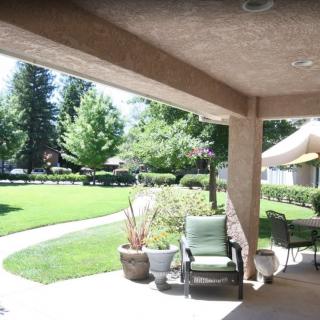 A sunny patio with outdoor seating overlooking a lush green lawn.