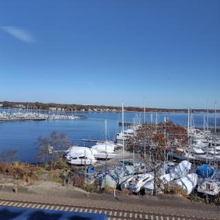 A serene view of a marina on a clear autumn day, with boats docked by the waterfront.