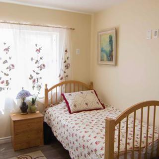 A cozy bedroom with a single bed, wooden furniture, and floral curtains.