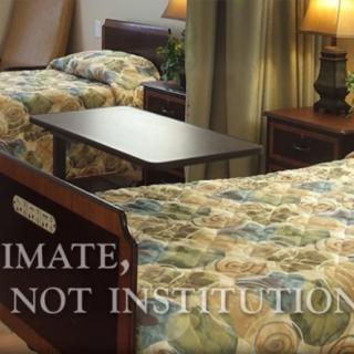 A cozy bedroom setting with two beds and floral bedspreads, accented by lamps and curtains.