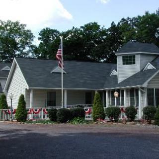 A residential house with an American flag, surrounded by trees and landscaping.