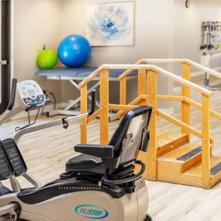 A physical therapy room equipped with exercise machines and fitness balls.