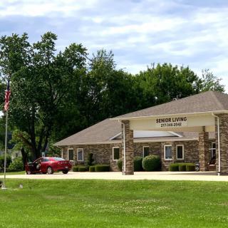 A small bank building surrounded by trees and greenery with a parked car nearby.