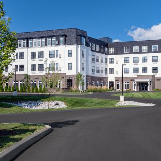 A modern residential building surrounded by well-maintained landscaping on a sunny day.