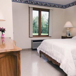 A cozy bedroom with a bed, lamps, and a window overlooking greenery.