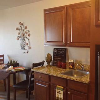 A cozy kitchen with wooden cabinets, a small dining table set, and decorative wall art.