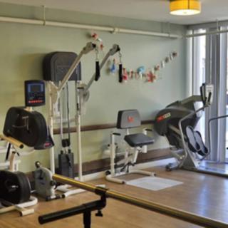A small indoor gym with various fitness equipment, including an exercise bike and an elliptical machine.