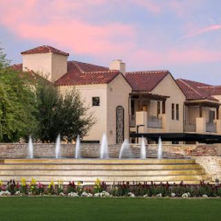 A stunning luxury home featuring elegant architecture and a beautiful fountain at sunset.