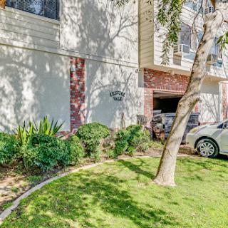 A well-maintained apartment exterior featuring landscaped greenery and parking.