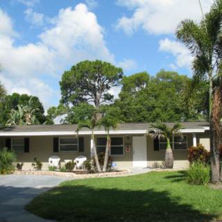 A suburban house with palm trees and a driveway in a sunny setting.