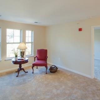A cozy living room with a red chair, side table, and a lamp by the window.