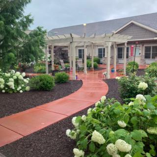 A beautifully landscaped garden with a winding pathway and pergola leads to a house.