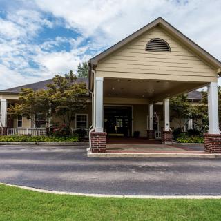 A large building with a covered entrance and landscaped surroundings.