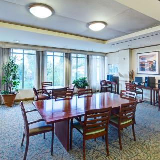 A spacious conference room with a large meeting table and chairs, surrounded by windows and plants.