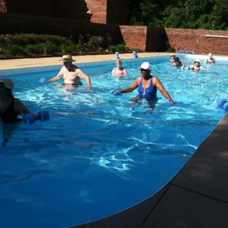 A group of people engaging in water exercises in an outdoor swimming pool.