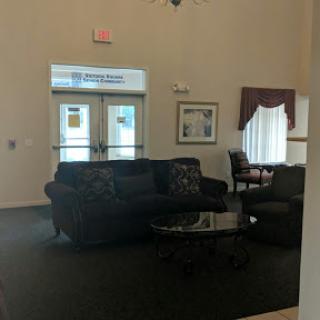A cozy lobby area featuring a comfortable couch and a glass coffee table, designed for relaxation and socializing.