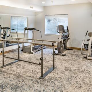 A well-lit gym with various exercise machines and mirrors for workouts.