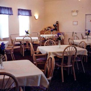 A cozy dining area with neatly arranged tables and chairs, adorned with simple floral decor.