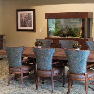 A stylish dining area with a large wooden table, elegant chairs, and an aquarium as the centerpiece.