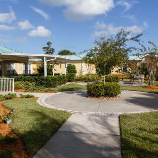 A well-maintained garden with a circular pathway and surrounding greenery under a partly cloudy sky.
