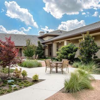 A beautifully landscaped garden with a patio and seating area under a partially cloudy sky.