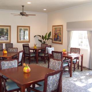 A neatly arranged dining area with multiple tables and chairs, decorated with artwork and plants.