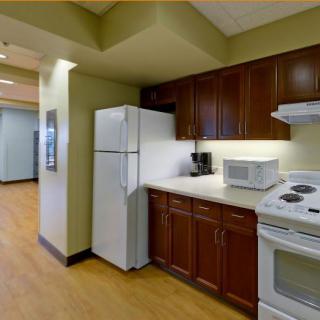 A modern kitchen featuring wooden cabinets, a refrigerator, stove, and microwave.