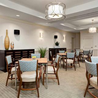 A well-lit dining room featuring modern decor with several tables and chairs arranged neatly.