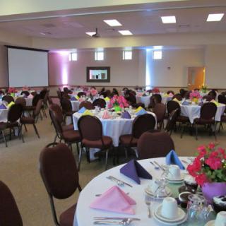 A beautifully arranged banquet hall ready for an event, featuring decorated tables and a projector screen.