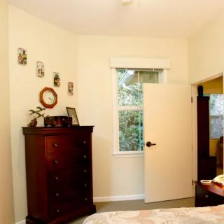 A cozy bedroom corner with a wooden dresser and a window letting in natural light.