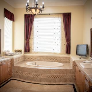 A luxurious bathroom featuring a large bathtub, elegant chandelier, and classic decor.