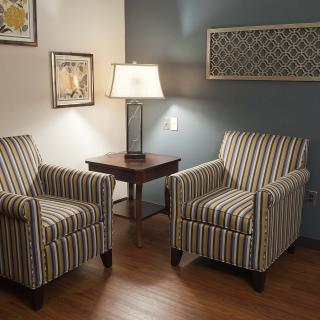 A cozy living room corner with two striped armchairs and a lamp on a side table.