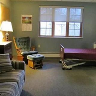 A hospital room with a patient bed, chair, and window.